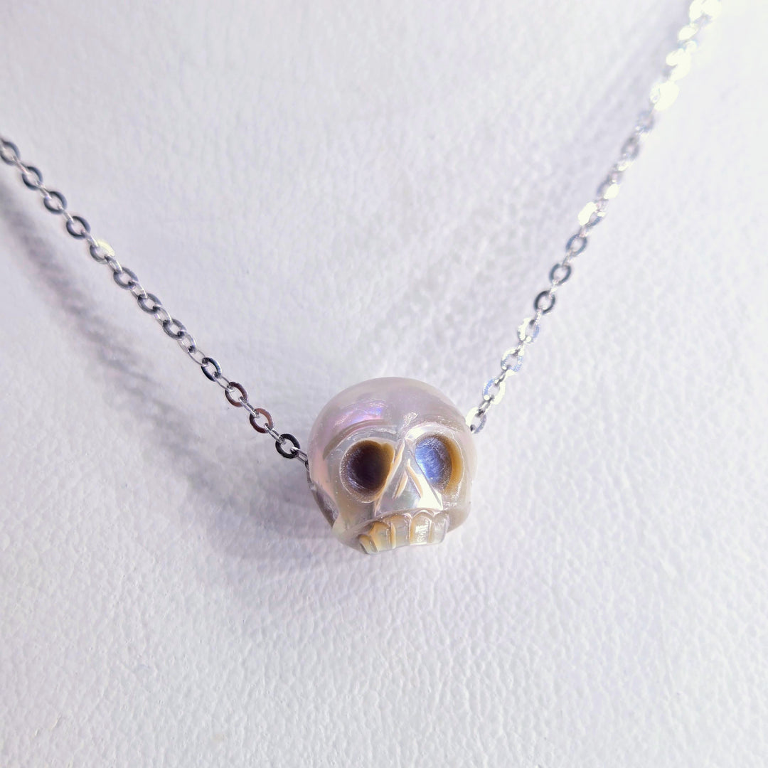 Skull-shaped pendant on a chain against a white background