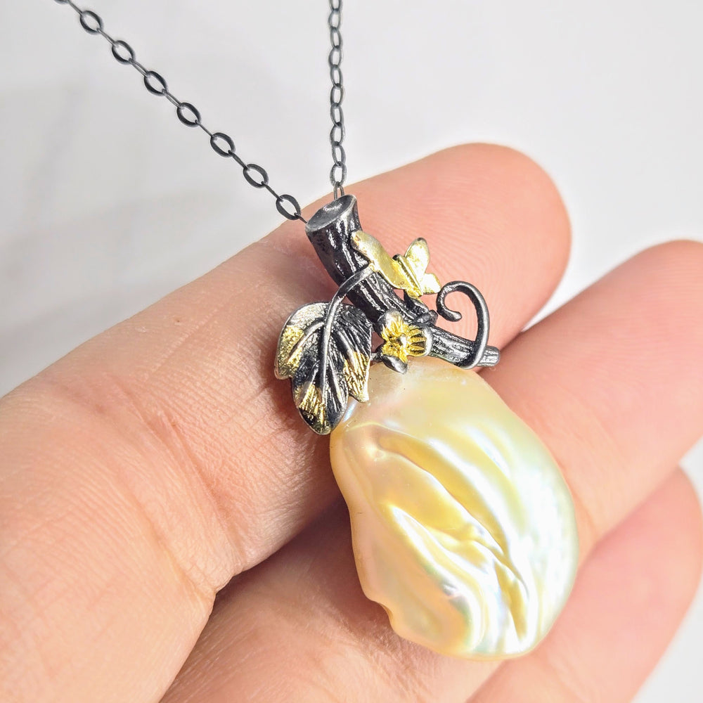 Pearl pendant necklace held in a hand with a plain background
