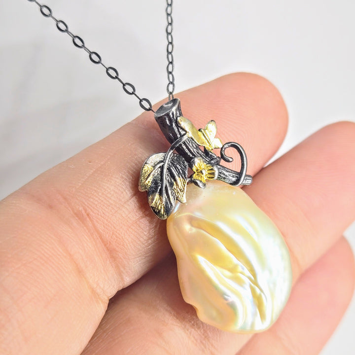 Pearl pendant necklace held in a hand with a plain background