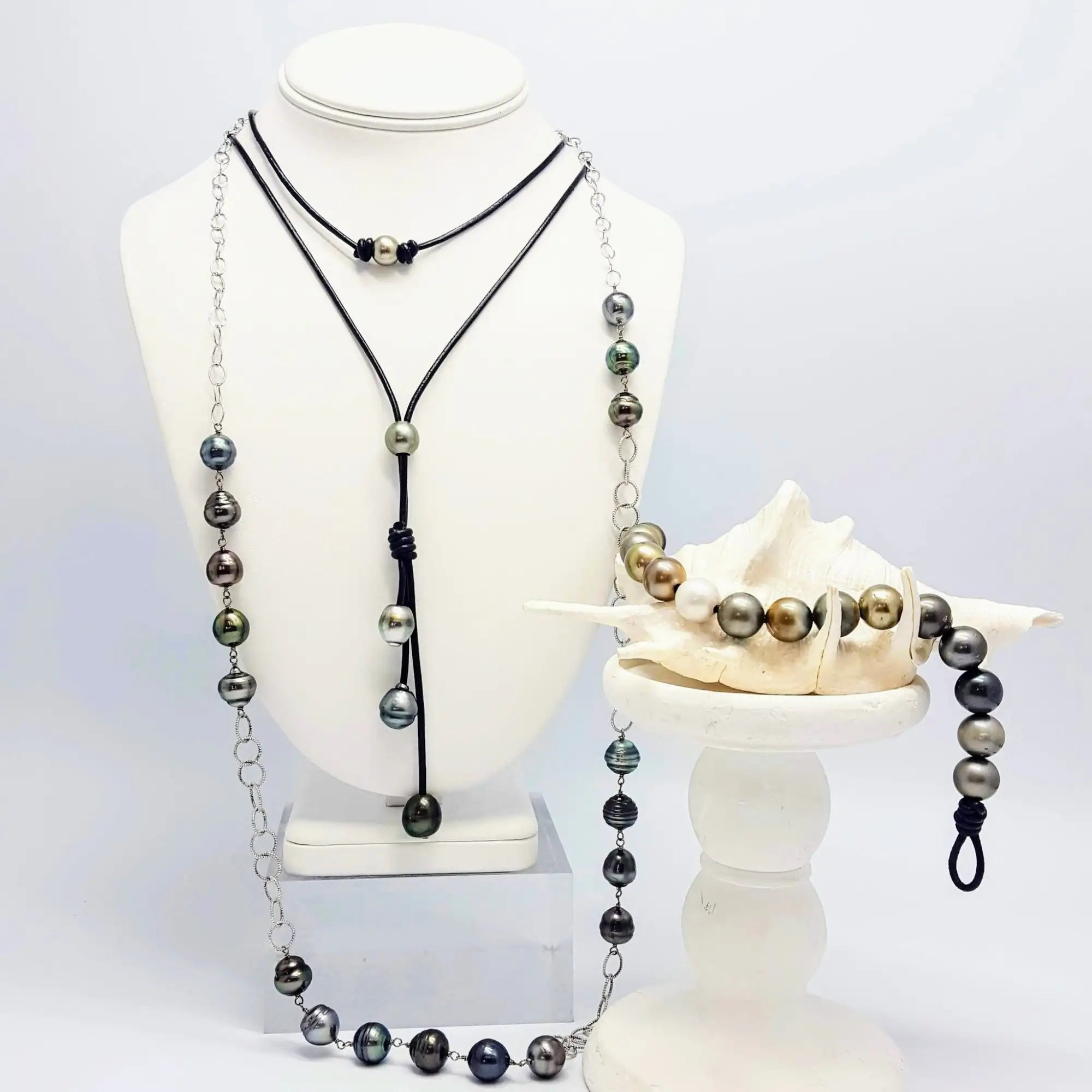 Elegant multi-strand necklace featuring black cord and silver chain with iridescent tahitian pearls in shades of gray, green, and gold.