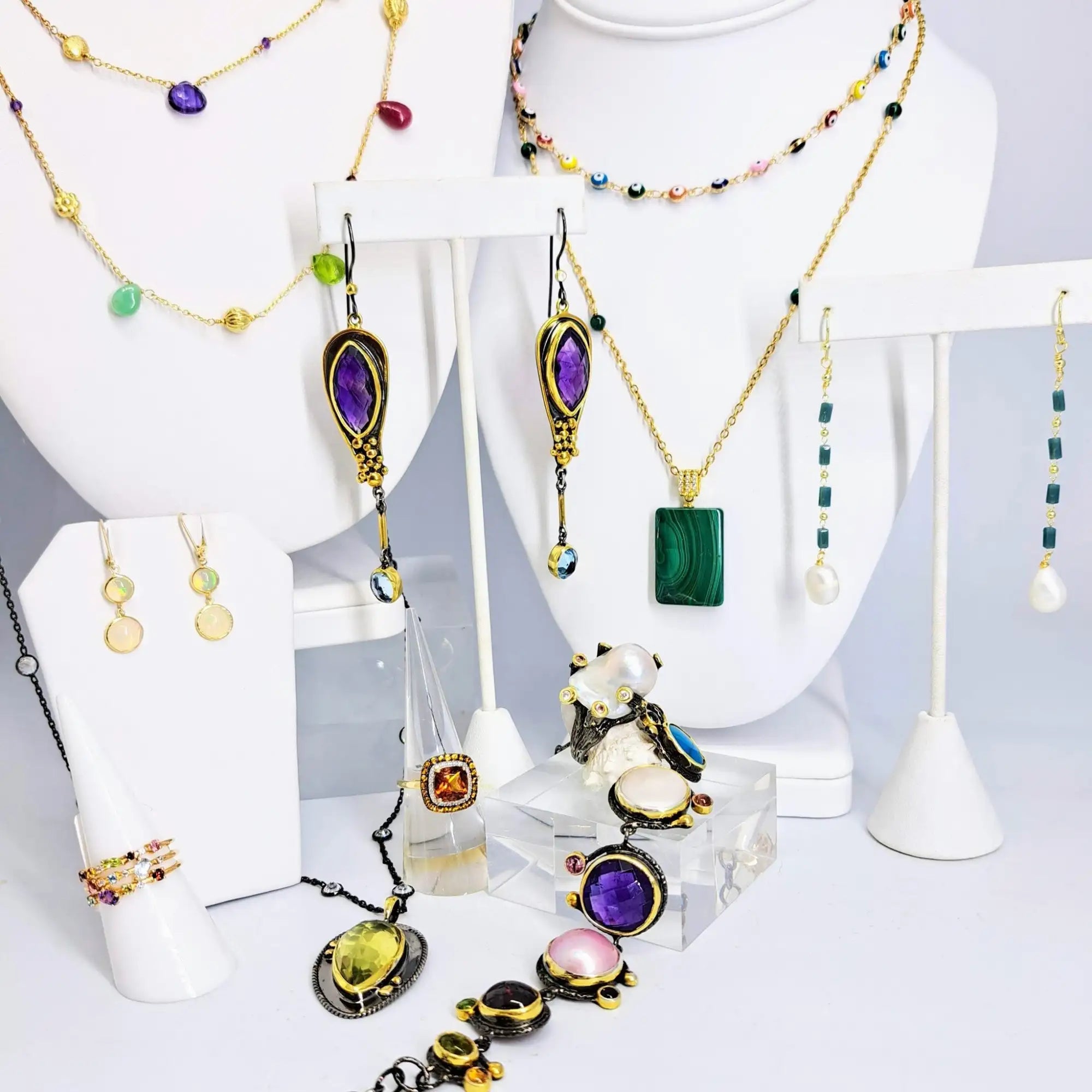 A pair of elegant, elongated earrings featuring deep purple amethyst stones set in ornate gold-toned metalwork with dangling accents.