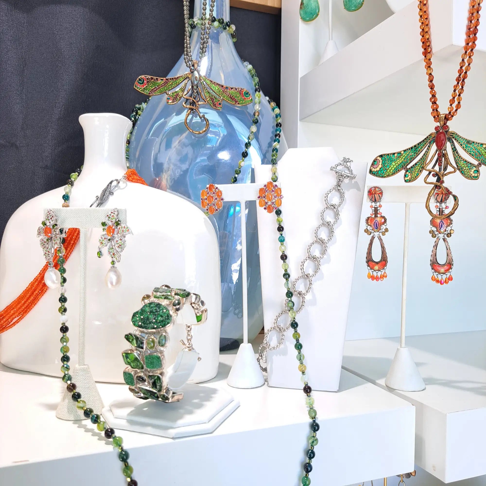 A vibrant green and orange dragonfly pendant necklace with intricate gemstone detailing.